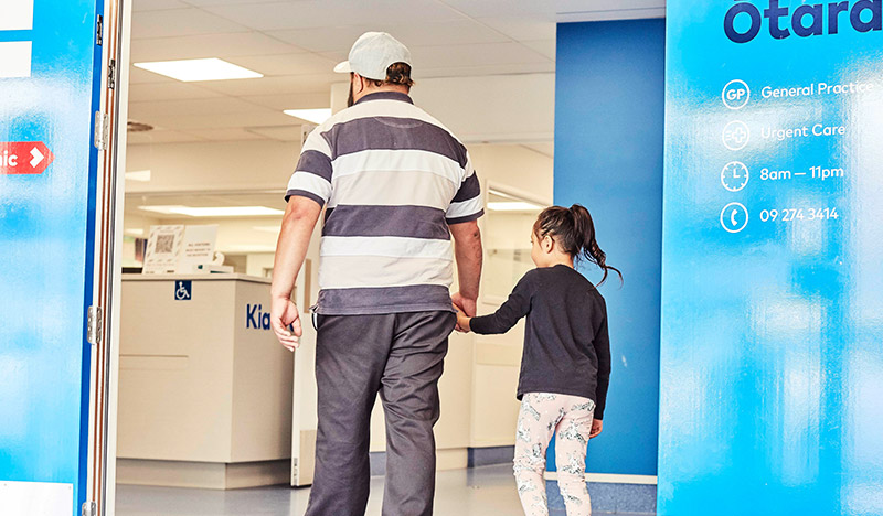 A photograph of an adult and child entering a Tamaki Health clinic